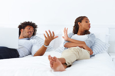 Portrait of a young African American couple lying on the bed and arguing
