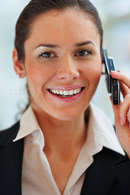 Closeup of young happy business woman smiling and communicating on mobile