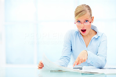 Portrait of blond female surprised while reading newspaper