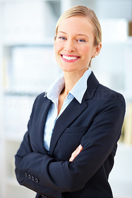 Confident young blond businesswoman standing with crossed arms