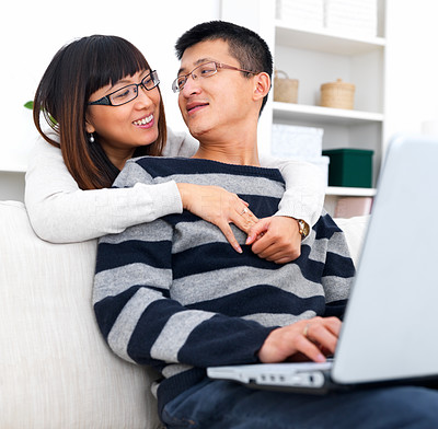 Asian lady embracing man using laptop