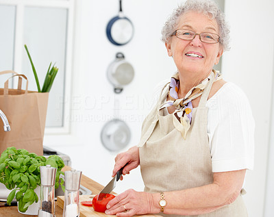 Closeup of an old woman smiling and chopping tomatoes