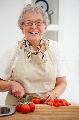 Closeup of an old woman smiling and chopping tomatoes