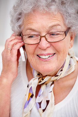 Closeup of an old woman smiling and using a cellphone