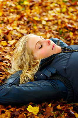 Woman lying on fallen leaves with eyes closed