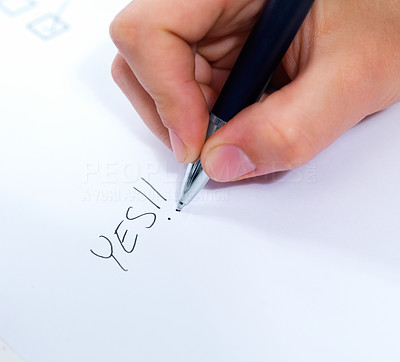 Macro of a hand writing yes on white paper