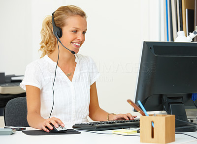 Closeup of a young woman using a computer with headset