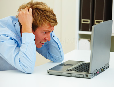 Portrait of young frustrated man looking at laptop