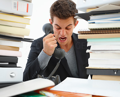 Closeup of a young angry business man shouting over a telephone