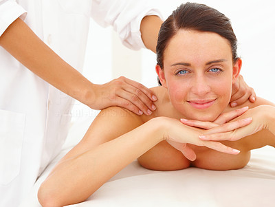 Naked young woman getting shoulder massage at spa