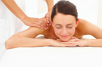 Smiling young woman getting shoulder massage at spa