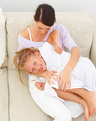 Mother with daughter playing on couch at home