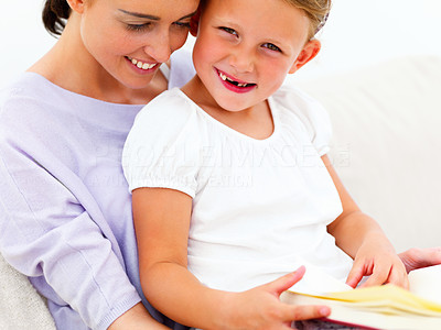 Smiling young mother with her daughter reading book