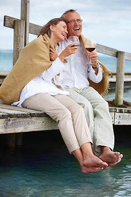 Romantic old couple sitting on jetty by sea