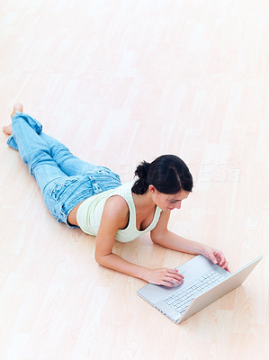 Modern Young lady lying on floor, working on notebook