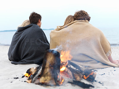 Young Couples sitting by bonfire at beach