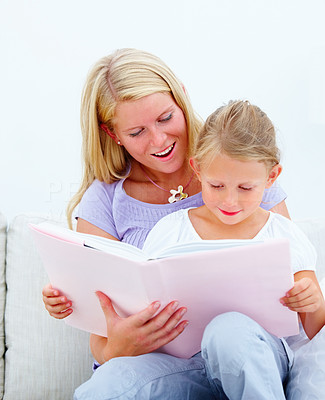 Mother with her cute daughter reading a book against white background