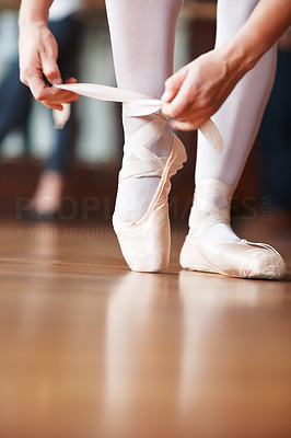 Ballerina putting her shoes on with a blurred man in background