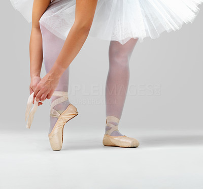 Ballerina putting on her ballet shoes against white background