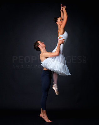 Two graceful ballet dancers performing against black background