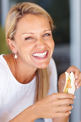 Closeup of a happy beautiful mature woman eating sandwich