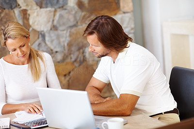 Mature couple doing home finance at dining table , using laptop