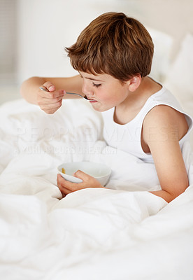Small boy having healthy breakfast on bed