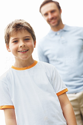 Young boy standing with his father in background