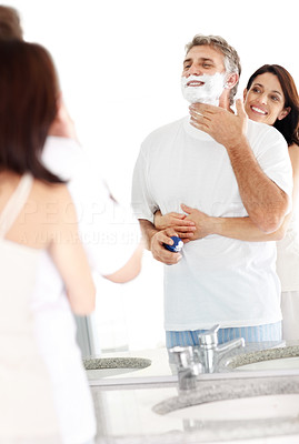 Morning routine - Mature man shaving with his wife hugging him