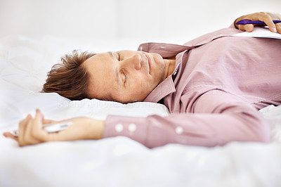 Tired Businessman sleeping on bed with cellphone in hand