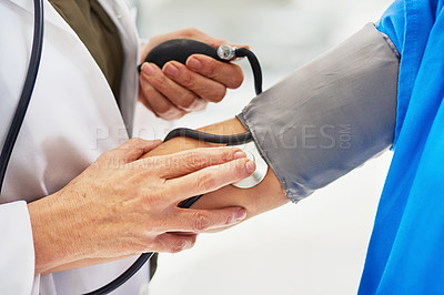 Buy stock photo Cropped shot of a doctor checking a patient’s blood pressure