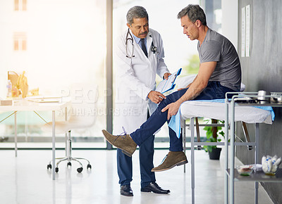 Buy stock photo Shot of a mature doctor examining his patient who is concerned about his knee