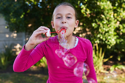 Buy stock photo Portrait of a cute young girl blowing bubbles outside