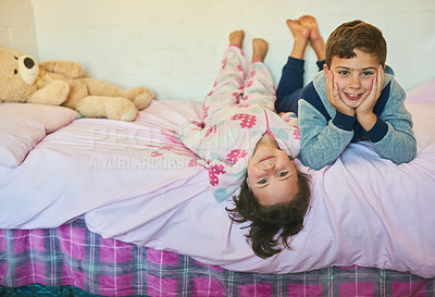 Buy stock photo Shot of two young siblings lying down together on a bed at home