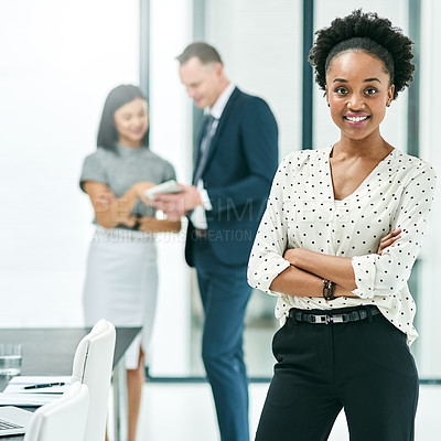 Buy stock photo Cropped portrait of a young businesswoman standing in the office with her colleagues in the background