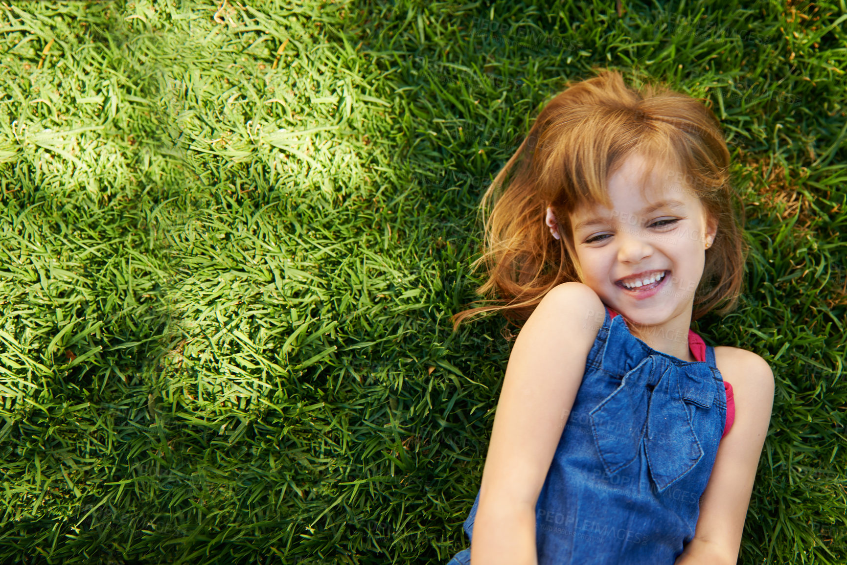 Shot of a cute little girl smiling while lying down on grass - stock photo ...