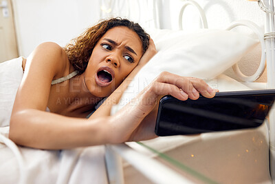 Buy stock photo Shot of a young woman lying in bed in the morning at home and looking shocked while checking her cellphone