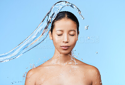 Buy stock photo Shot of a beautiful young woman being splashed with water against a blue background