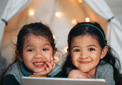 Buy stock photo Shot of two sisters using a digital tablet at home