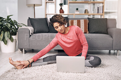 Buy stock photo Shot of an attractive young woman using a laptop while stretching on the lounge floor at home