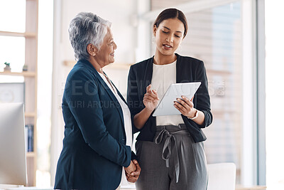 Buy stock photo Cropped shot of two attractive businesswomen looking at a tablet in their office