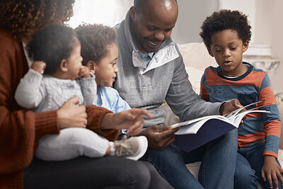 Buy stock photo Shot of a father reading a book to his family at home
