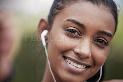 Buy stock photo Portrait of a sporty young woman wearing earphones and taking selfies while exercising outdoors