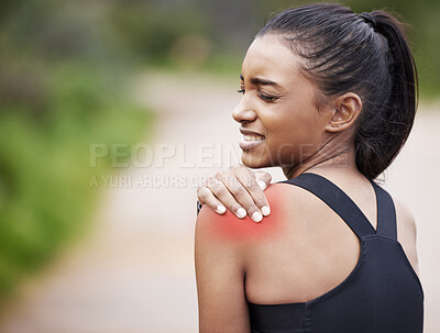 Buy stock photo Shot of a sporty young woman experiencing shoulder pain while exercising outdoors
