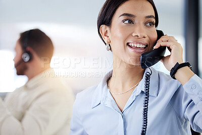 Buy stock photo Shot of an attractive young call centre agent sitting with her colleague in the office and using a telephone