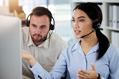 Buy stock photo Shot of two young call centre agents sitting together in the office and having a a discussion