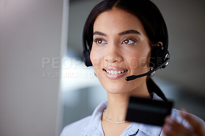 Buy stock photo Shot of a young call centre agent sitting in the office and holding a credit card while using her computer