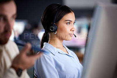 Buy stock photo Shot of an attractive young call centre agent sitting with her colleague in the office and using her computer