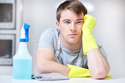 Buy stock photo Shot of a young man looking bored while cleaning his kitchen