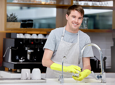 Buy stock photo Shot of a young man washing dishes in his kitchen